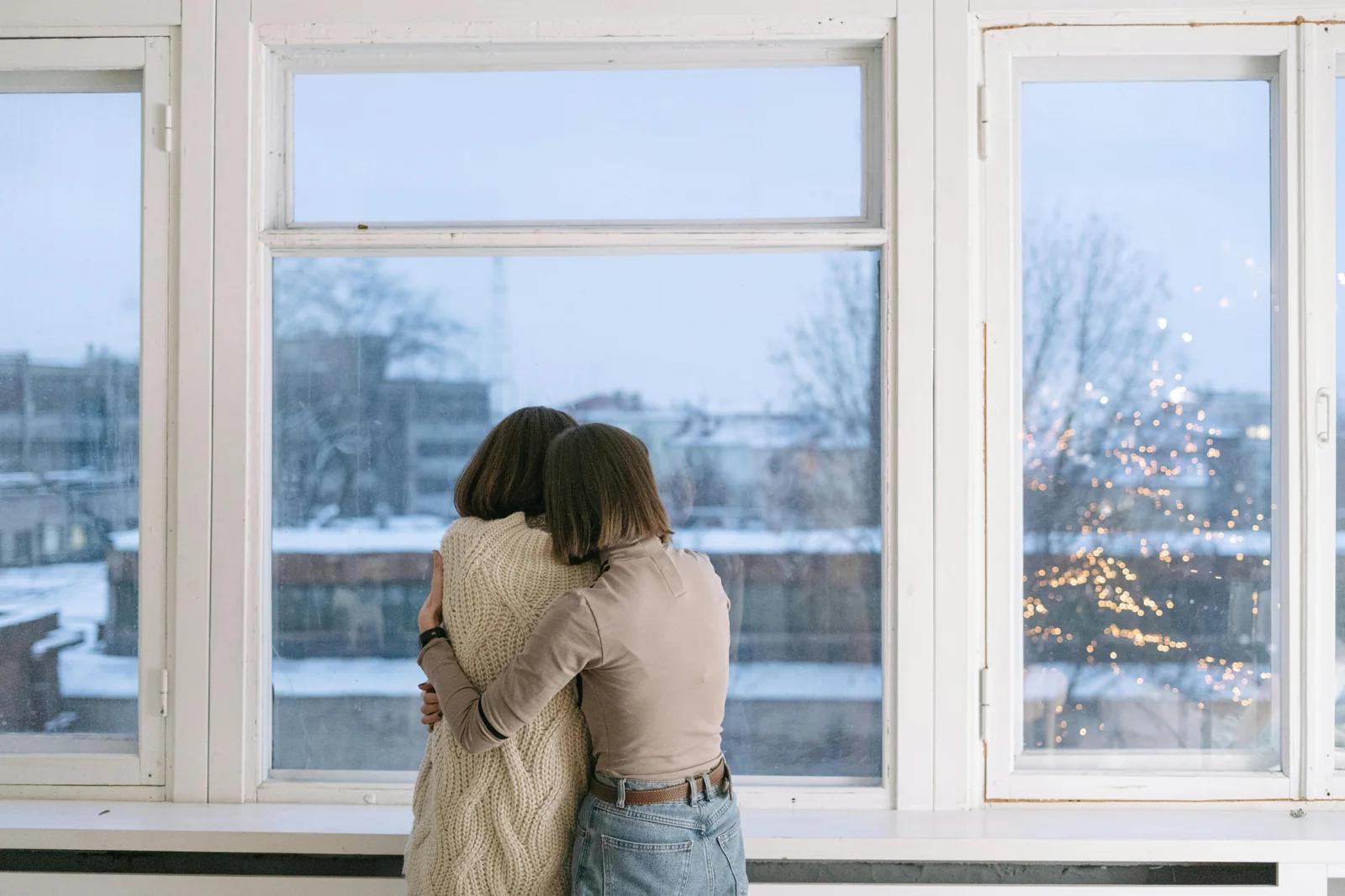 Una pareja se abraza junto a una ventana luminosa